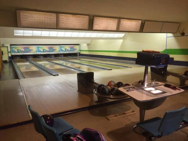 Historic bowling alley with a foreground manual scoring projection console and overhead scoring displays